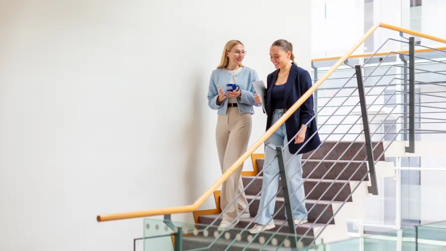 2 Auszubildende laufen lächelnd die Treppe runter und unterhalten sich